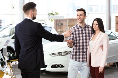 Young couple buying new car in salon