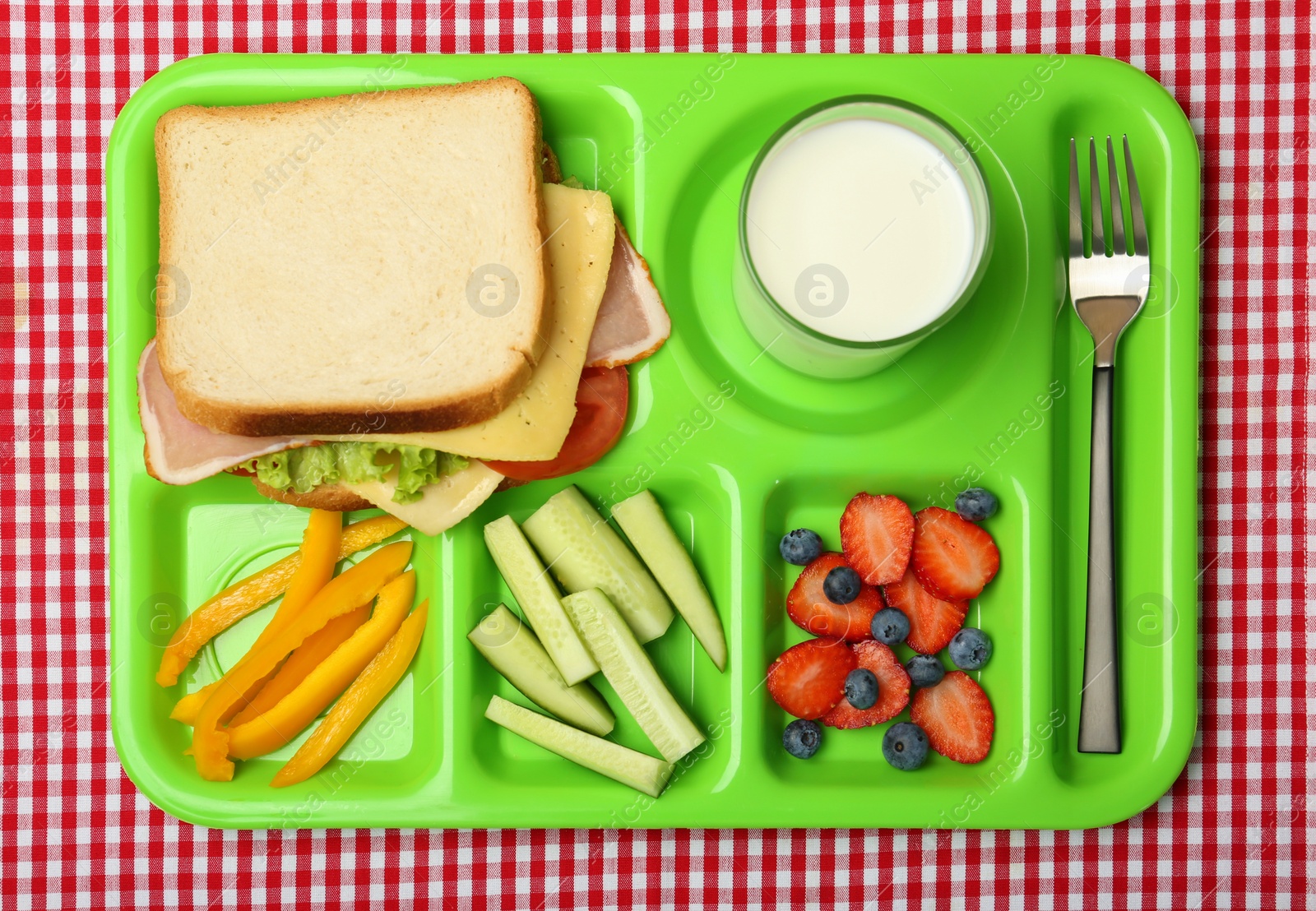 Photo of Serving tray with healthy food on tablecloth, top view. School lunch