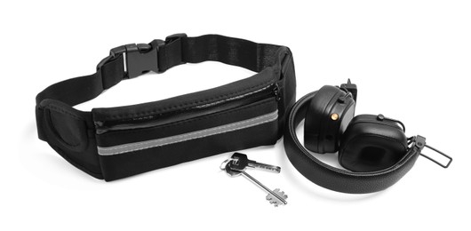 Photo of Stylish black waist bag, headphones and keys isolated on white