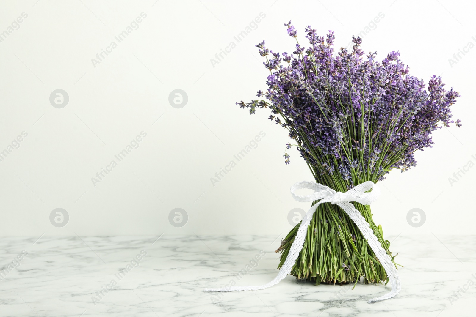 Photo of Beautiful lavender bouquet on marble table against white background. Space for text