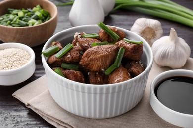 Tasty soy sauce and roasted meat on table, closeup