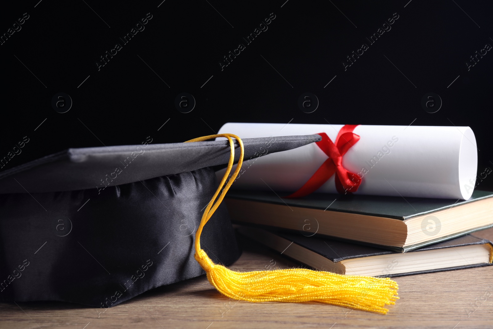 Photo of Graduation hat, books and student's diploma on wooden table