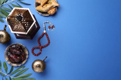 Photo of Flat lay composition with Arabic lantern and snacks on blue background. Space for text