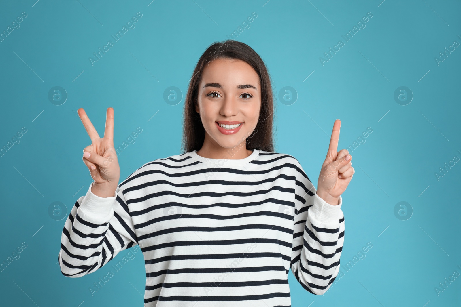 Photo of Woman showing number three with her hands on light blue background