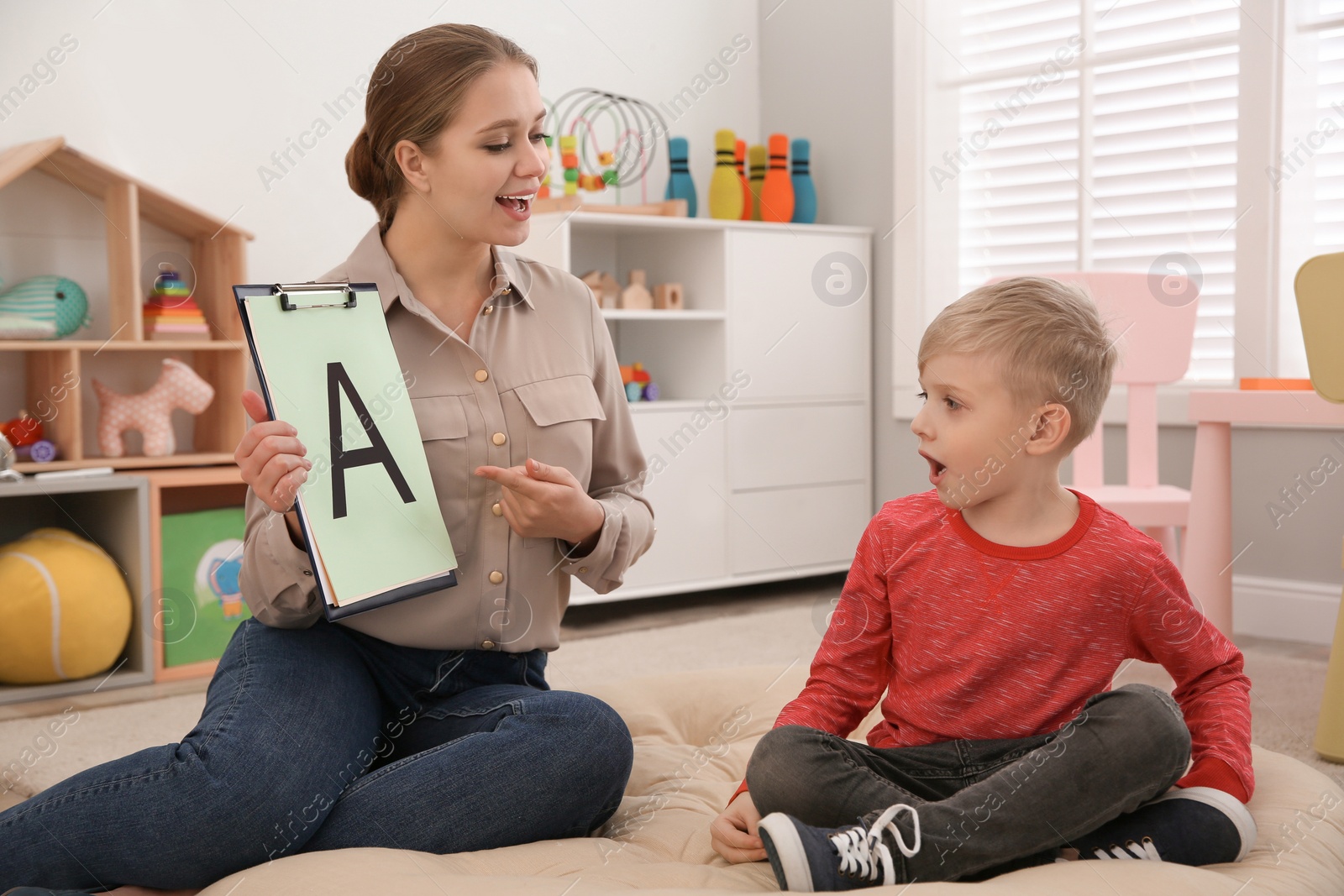 Photo of Speech therapist working with little boy in office