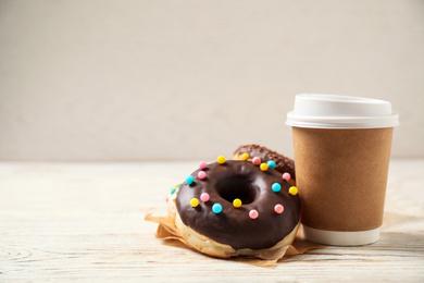 Delicious glazed donuts and coffee on white wooden table. Space for text