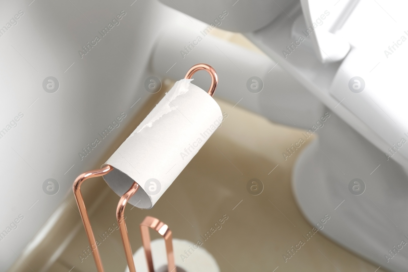 Photo of Holder with empty toilet paper roll in bathroom