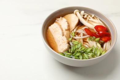 Delicious ramen with meat and mushrooms in bowl on white table. Space for text