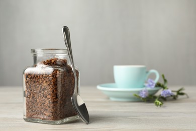 Jar of chicory granules and spoon on white wooden table, space for text