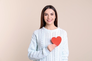 Photo of Portrait of young woman with paper heart on color background
