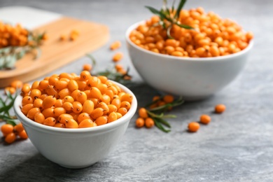 Photo of Fresh ripe sea buckthorn in bowl on grey table