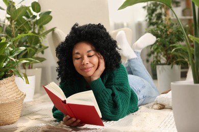 Relaxing atmosphere. Woman reading book surrounded by potted houseplants at home