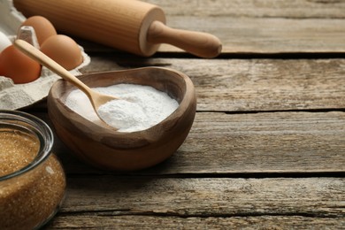 Photo of Baking powder, eggs, brown sugar and rolling pin on wooden table, closeup. Space for text