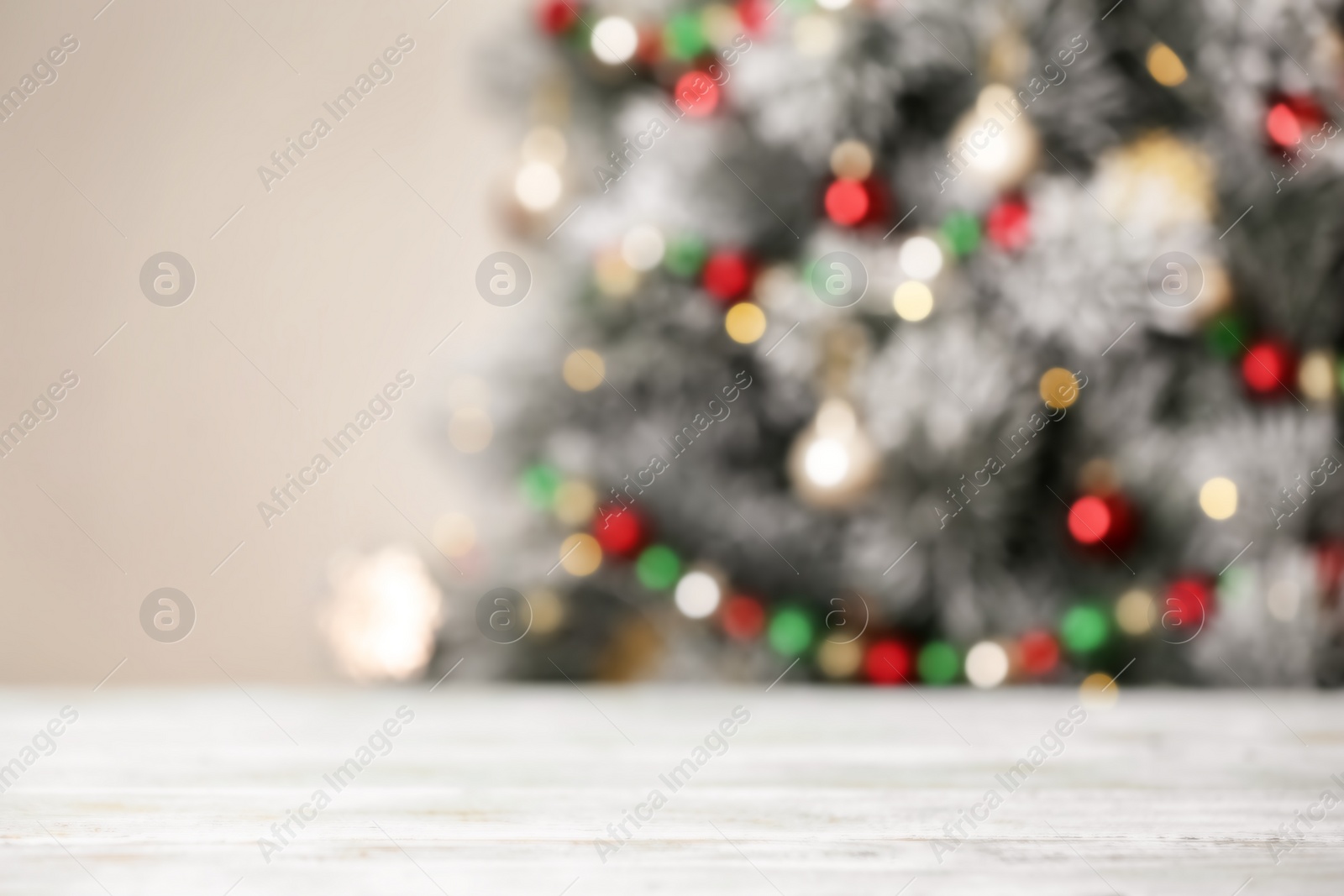 Photo of Empty white wooden table and blurred fir tree with Christmas lights on background, bokeh effect. Space for design