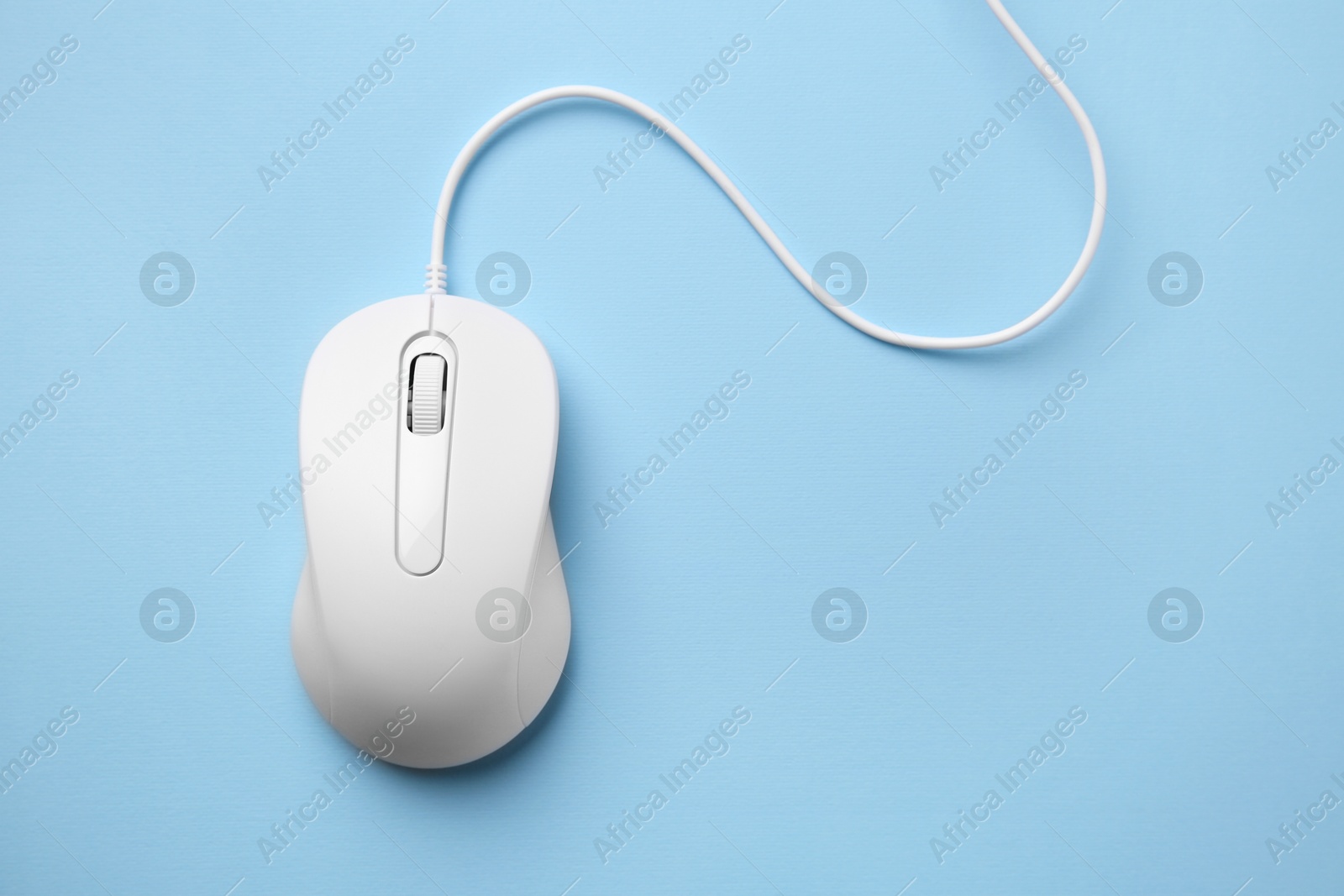 Photo of One wired mouse on light blue background, top view. Space for text