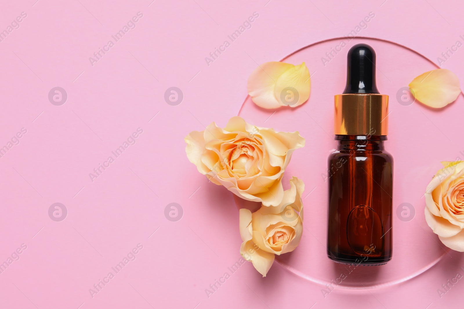 Photo of Bottle of cosmetic serum, flowers and petals on pink background, flat lay. Space for text