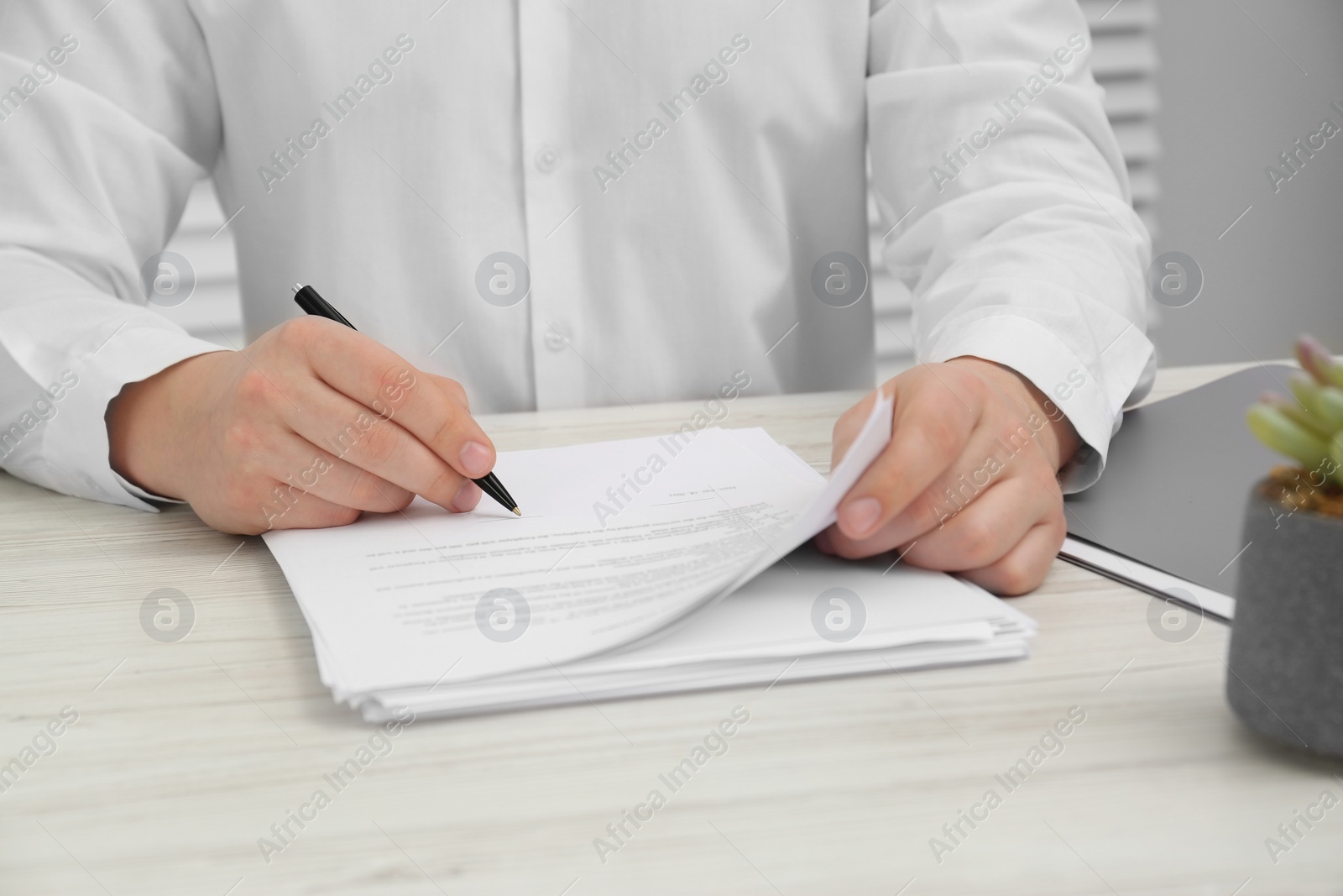 Photo of Man signing document at wooden table, closeup