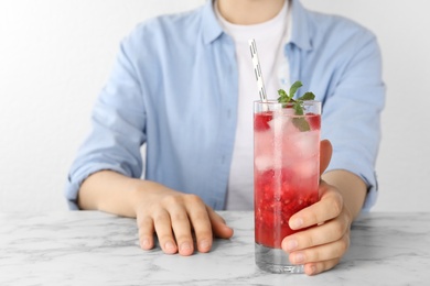 Woman with glass of raspberry refreshing drink at marble table, closeup