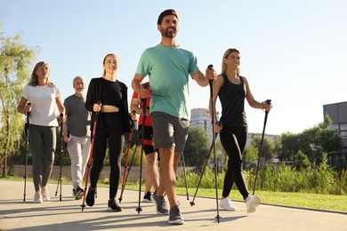 Photo of Group of people practicing Nordic walking with poles in park