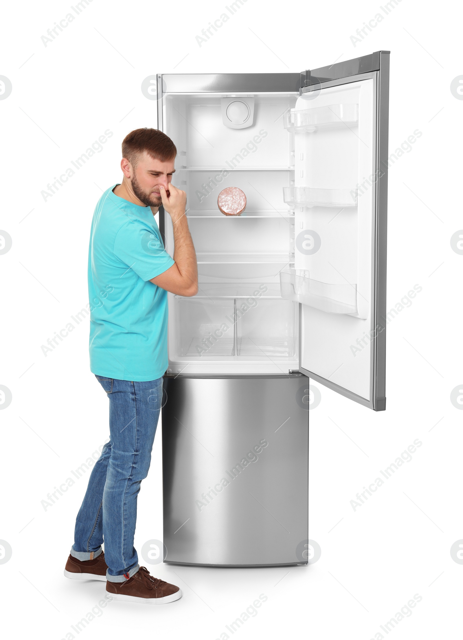 Photo of Young man near refrigerator with expired sausage on white background