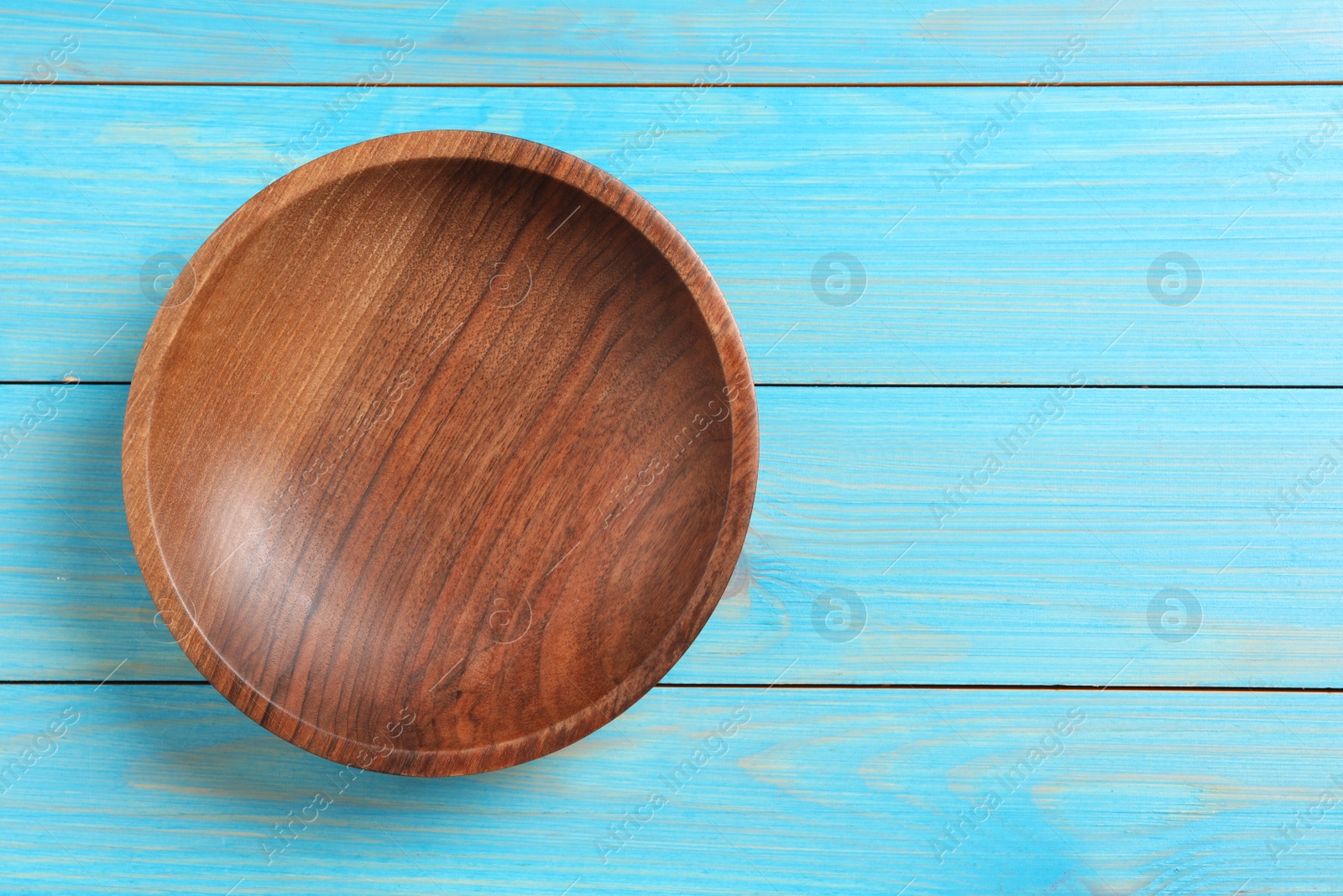 Photo of Empty clean wooden plate on turquoise table, top view. Space for text