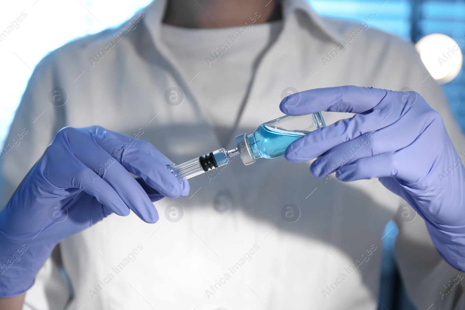 Photo of Woman filling syringe with vaccine from vial, closeup