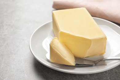 Photo of Plate with fresh butter and knife on table, closeup