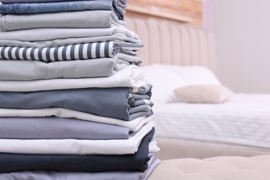 Photo of Stack of clean bed linens in bedroom. Space for text