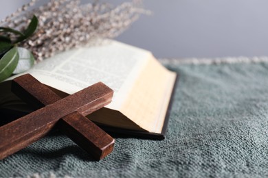 Photo of Wooden cross and Bible on table, closeup. Space for text