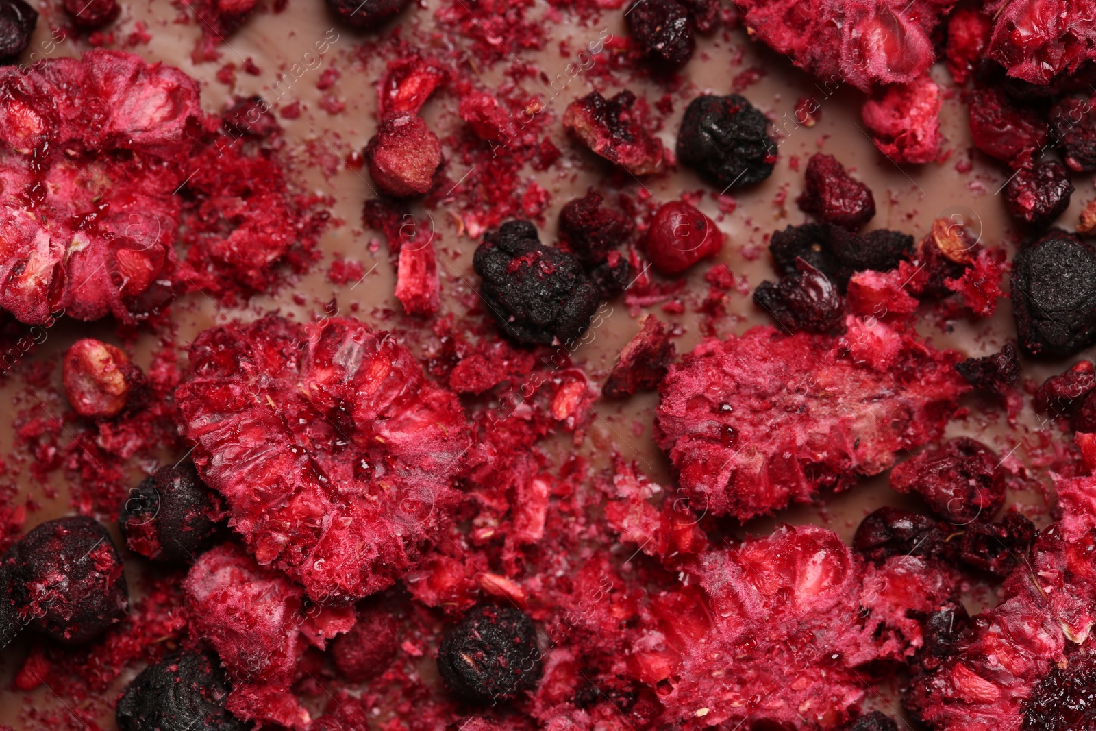 Photo of Chocolate bar with freeze dried berries as background, closeup