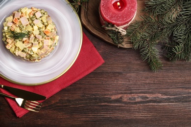 Flat lay composition with traditional russian salad Olivier on wooden table, space for text