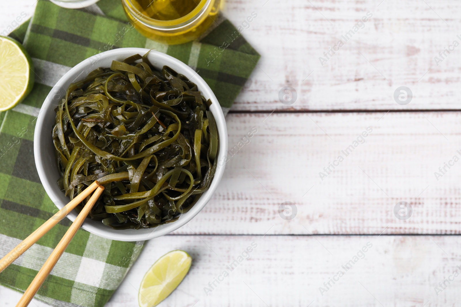 Photo of Tasty seaweed salad in bowl served on wooden table, flat lay. Space for text