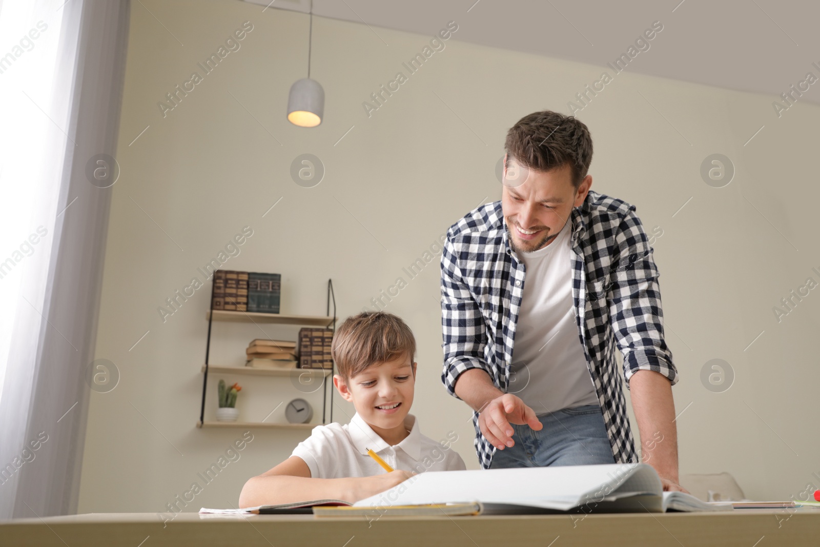 Photo of Dad helping his son with school assignment at home