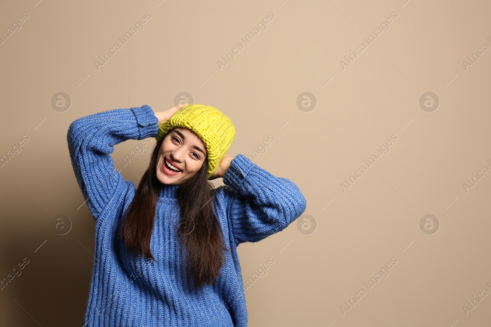 Photo of Young woman wearing warm clothes on color background, space for text. Winter season