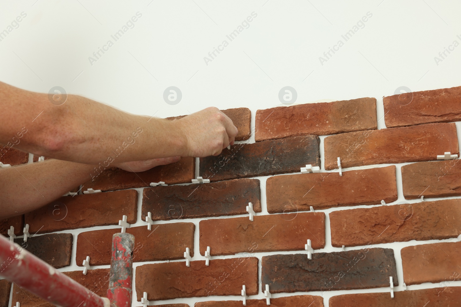 Photo of Professional builder gluing decorative brick on wall, closeup. Tiles installation process