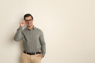 Young man with glasses on beige background. Space for text