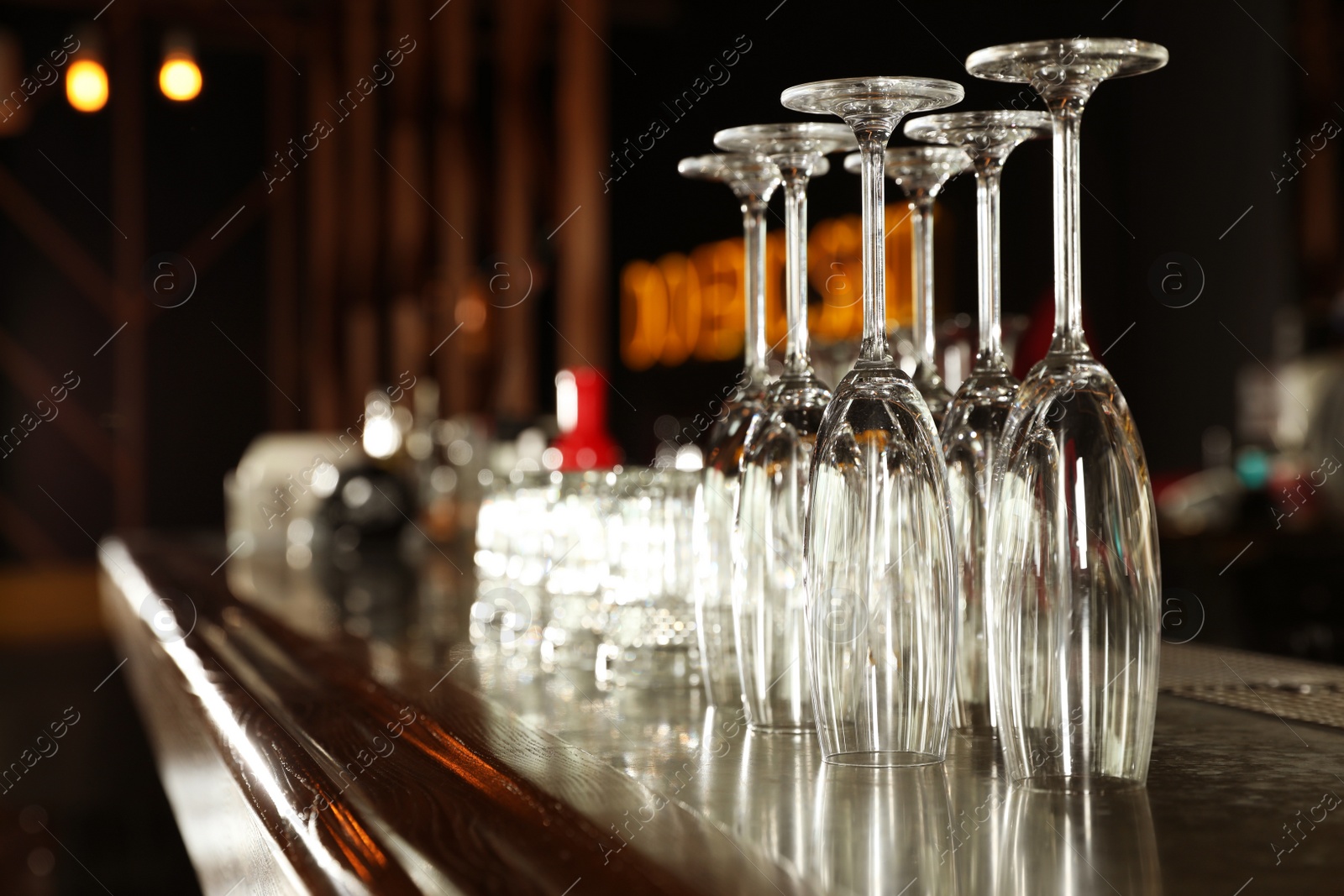 Photo of Different empty clean glasses on counter in bar. Space for text