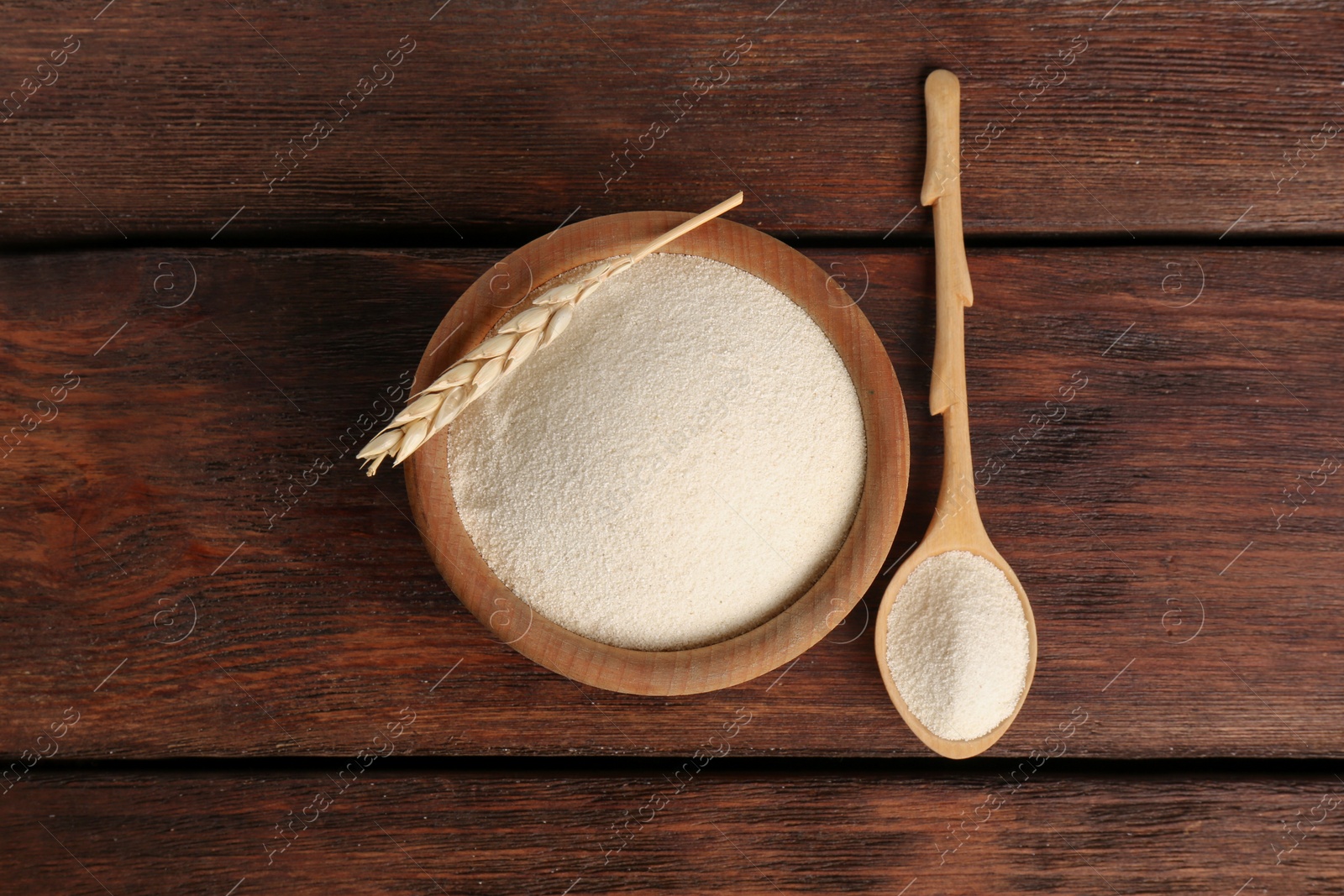 Photo of Semolina and spikelet on wooden table, flat lay