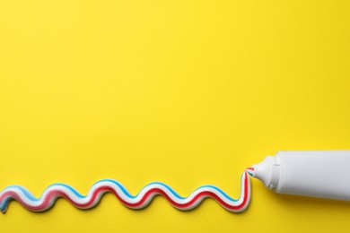 Photo of Blank tube with squeezed out toothpaste on yellow background, flat lay. Space for text