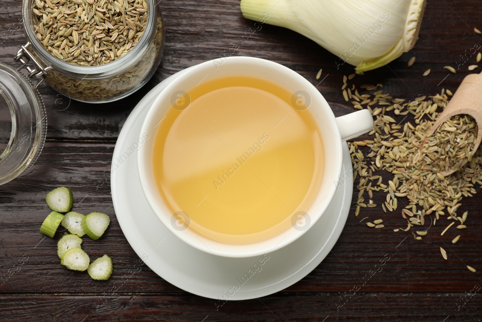 Photo of Fennel tea in cup, seeds and fresh vegetable on wooden table, flat lay