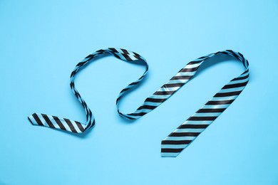 Photo of Striped necktie on light blue background, top view