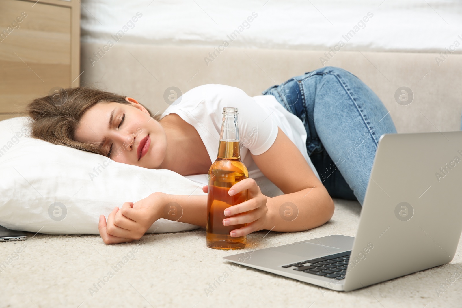 Photo of Lazy young woman with laptop and drink sleeping on floor at home