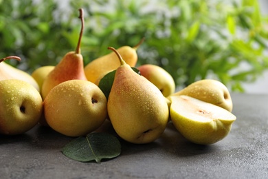 Photo of Ripe pears on grey table against blurred background