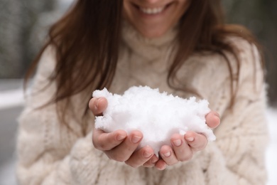 Young woman holding pile of snow in hands, closeup