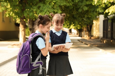 Little girls in stylish school uniform with tablet outdoors