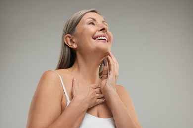 Photo of Beautiful woman with healthy skin on grey background, low angle view