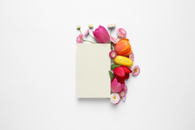 Photo of Beautiful composition with spring flowers and blank card on white background, top view. Space for text