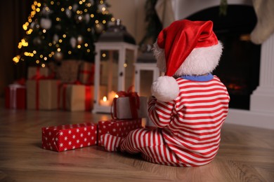 Photo of Baby in Christmas pajamas and Santa hat with gift boxes  indoors