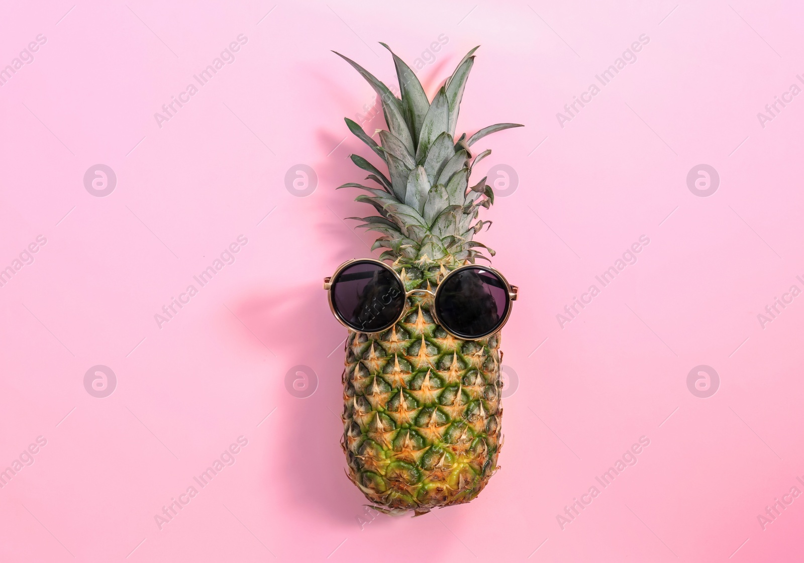 Photo of Fresh ripe pineapple with sunglasses on color background, top view