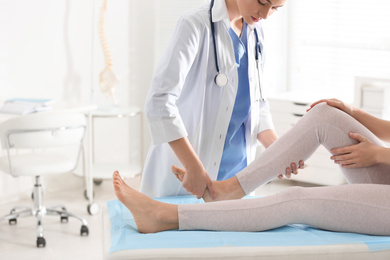 Photo of Female orthopedist examining patient's leg in clinic, closeup